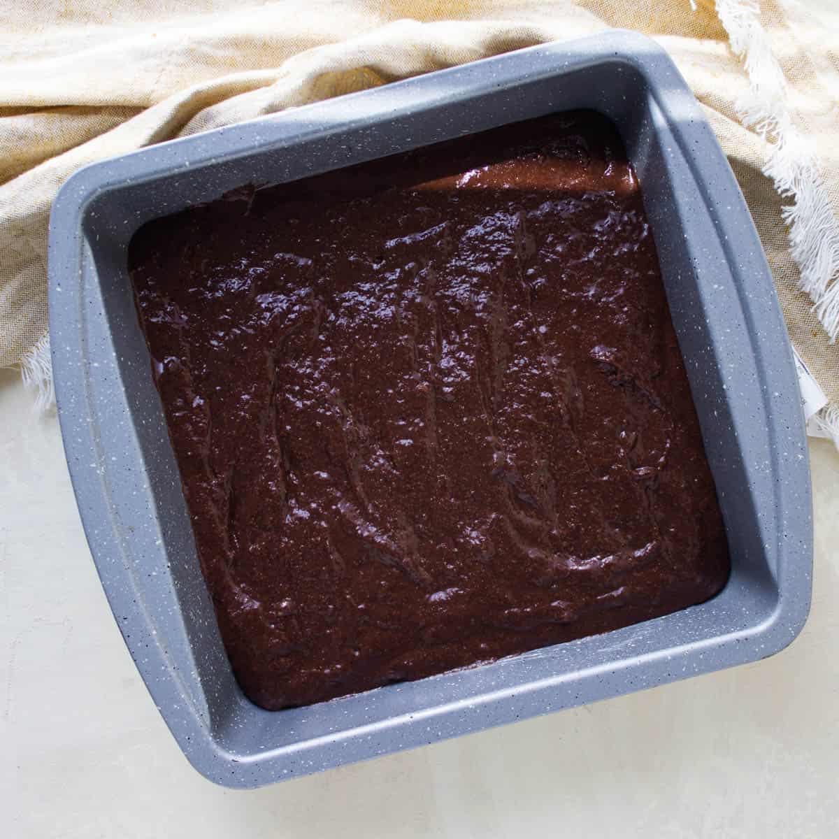 Chocolate banana cake batter in a square cake pan.