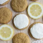 Top view of frosted, unfrosted cookies and lemon slices laying on brown parchment paper.