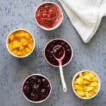 Five ramekins with different fruit toppings.