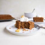 A slice of applesauce cake with whipped cream and apples on top.