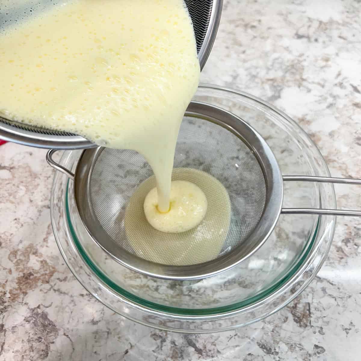 Pouring custard through a strainer.