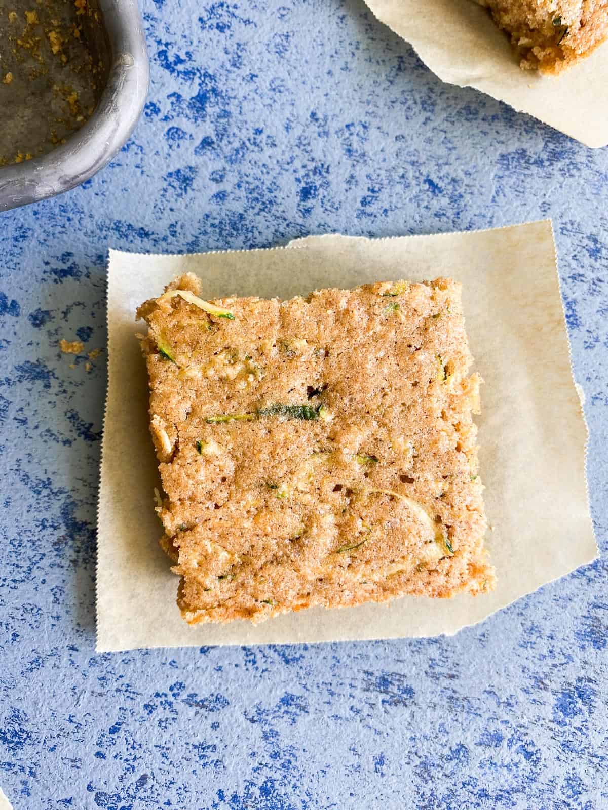 A piece of zucchini cake on a square of brown parchment paper.