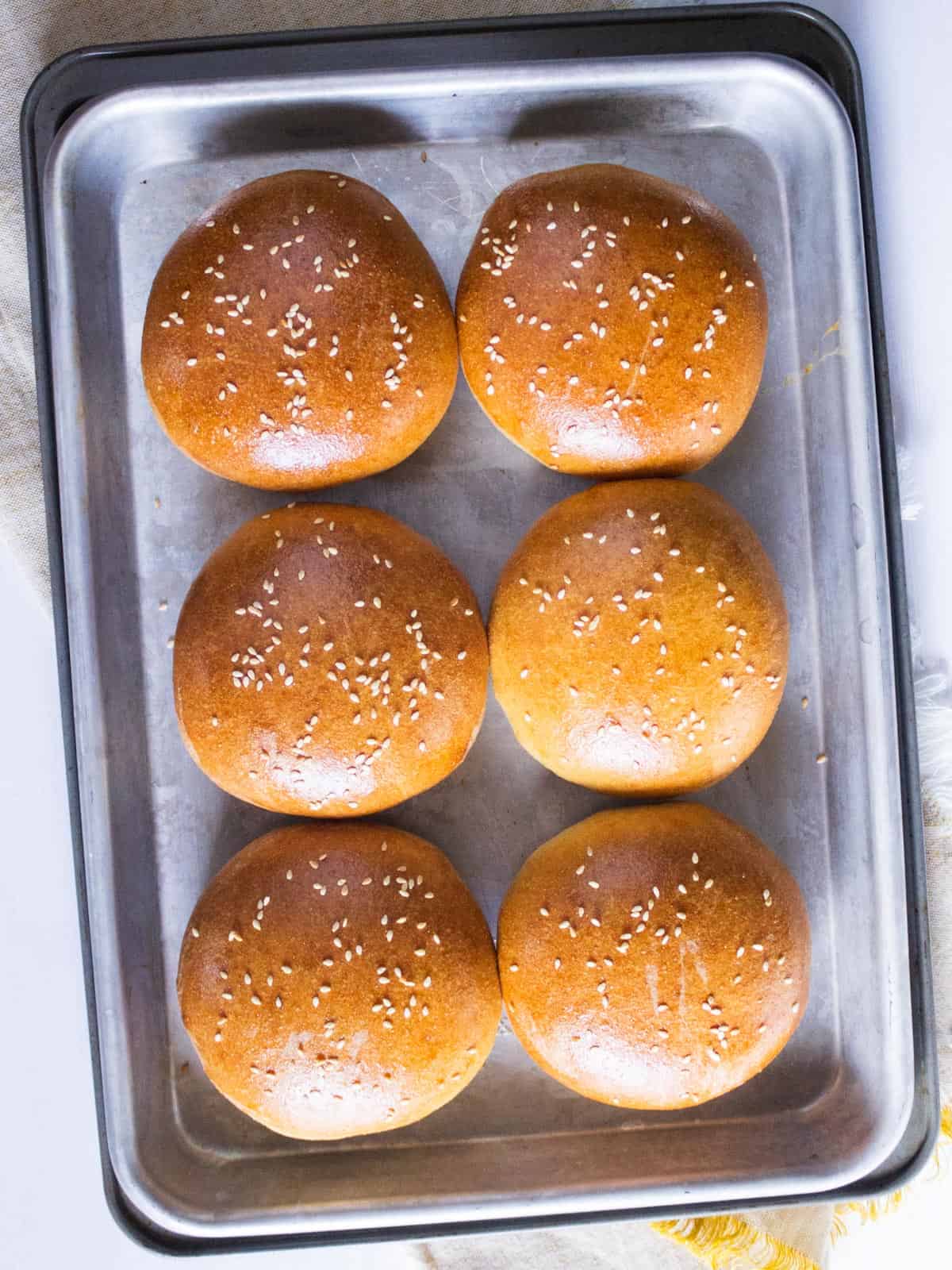 Hamburger buns on a baking tray.