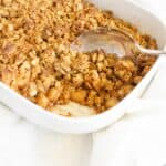 Scooping apple crisp out of the baking dish.