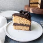 A slice of two layer vanilla cake with chocolate frosting on a plate.