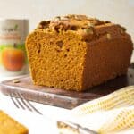 A loaf of pumpkin bread sitting on a wooden board.