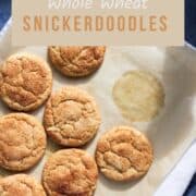 Whole wheat snickerdoodle cookies on a piece of parchment paper with text overlay.
