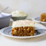 A slice of carrot cake with cream cheese frosting on a plate.