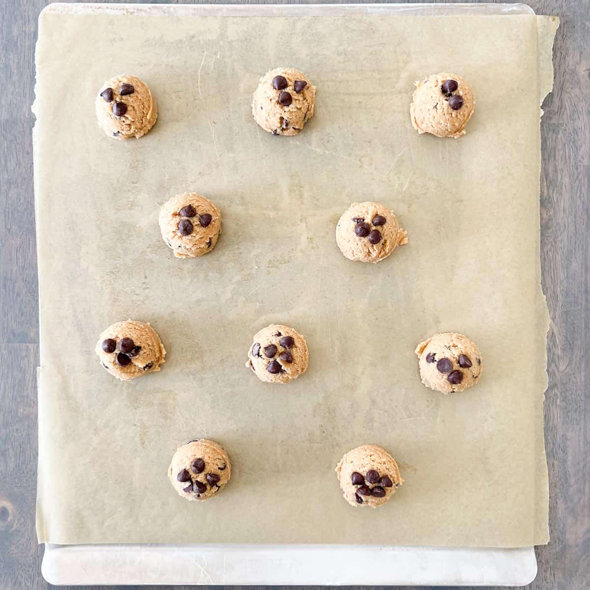 Whole wheat chocolate chip cookie dough on a baking sheet lined with parchment paper.