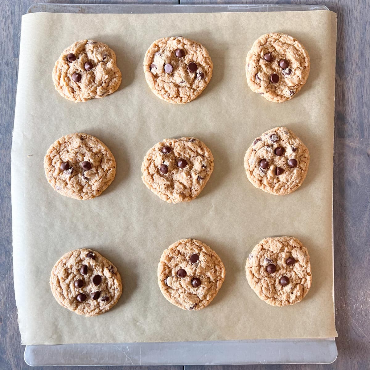 Whole wheat chocolate chip cookies on a baking sheet lined with parchment paper.