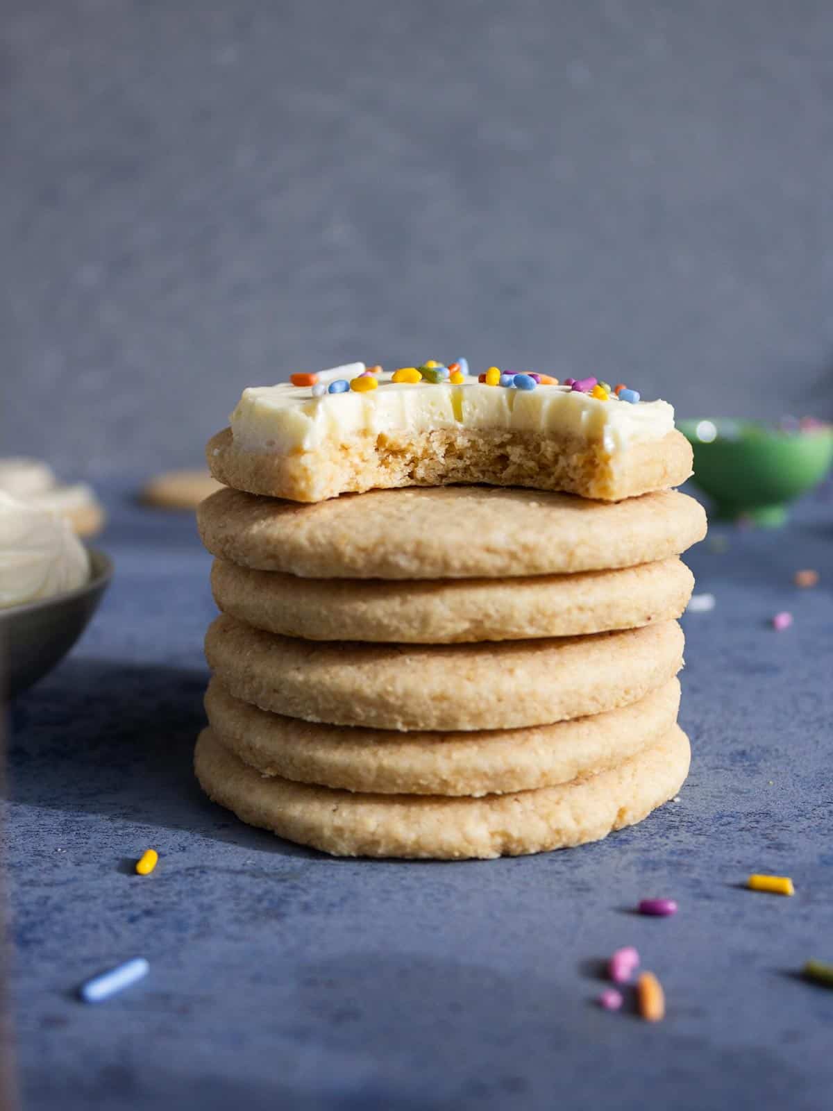 A stack of whole wheat sugar cookies, the top one frosted with sprinkles.