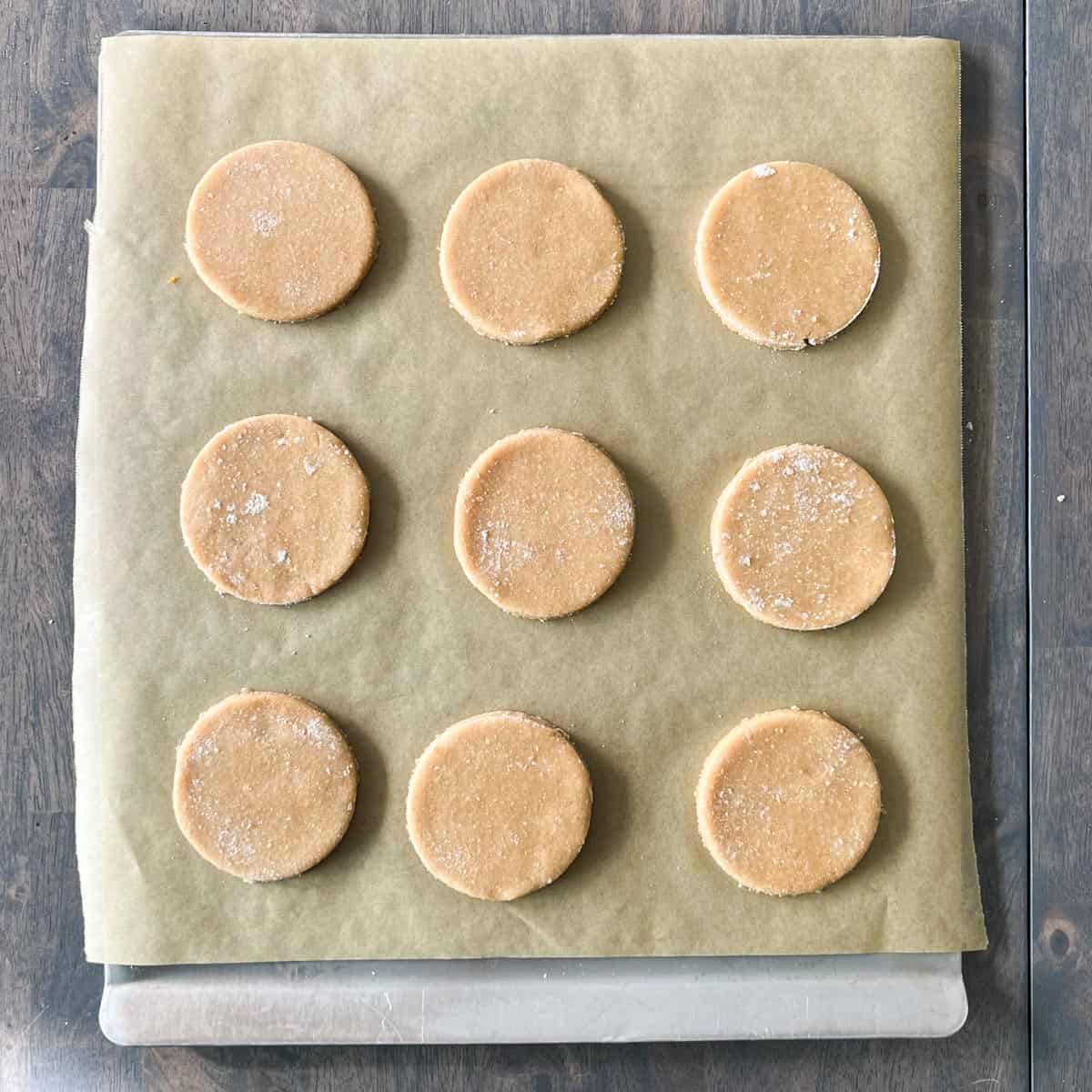 Round whole wheat cut out sugar cookies on a tray before baking.