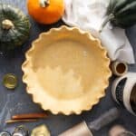 An unbaked whole wheat pie shell next to ingredients for making pumpkin pie.
