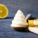 A round piped mound of lemon frosting on a wooden spoon.